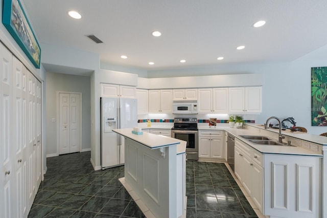 kitchen featuring a kitchen island, kitchen peninsula, sink, white cabinetry, and stainless steel appliances