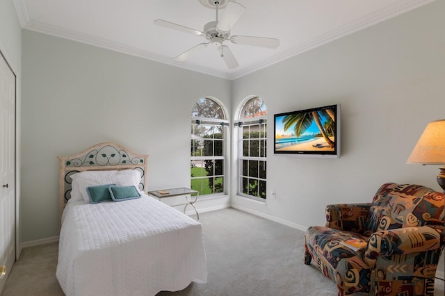 carpeted bedroom featuring ceiling fan, a closet, and ornamental molding