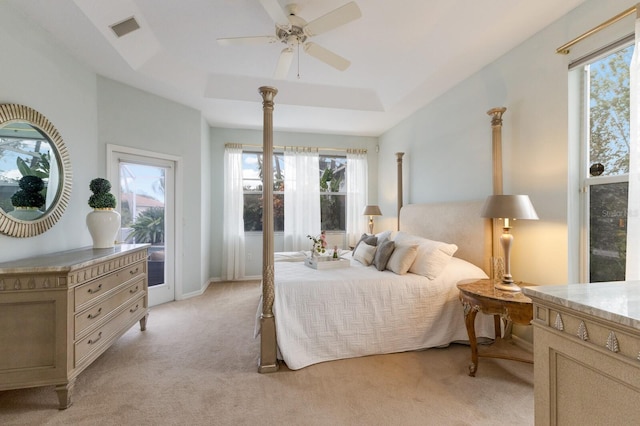 bedroom with ceiling fan, light colored carpet, and a tray ceiling