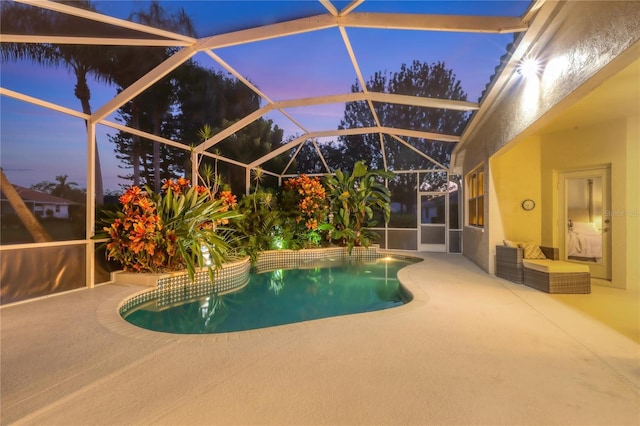 pool at dusk featuring a lanai and a patio