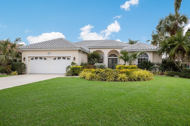 mediterranean / spanish home featuring a front yard and a garage