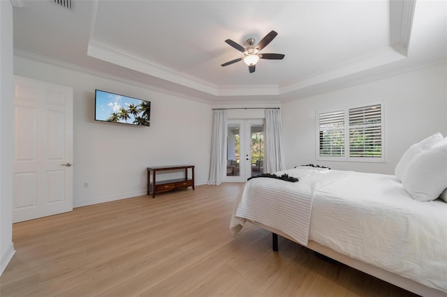 bedroom with a raised ceiling, french doors, light wood-type flooring, ceiling fan, and access to exterior