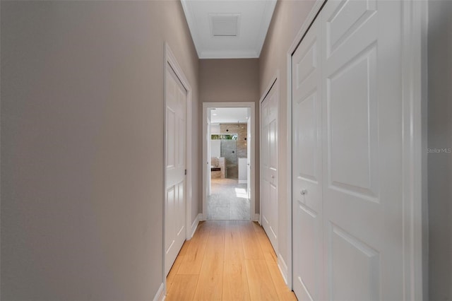 hall with ornamental molding and light hardwood / wood-style floors