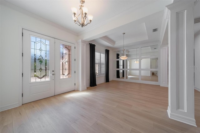 foyer featuring french doors, light hardwood / wood-style flooring, an inviting chandelier, and a tray ceiling