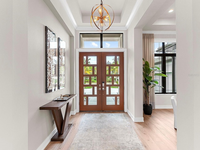 entryway featuring french doors, a raised ceiling, and light hardwood / wood-style floors