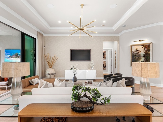 living room with ornamental molding, a tray ceiling, light hardwood / wood-style flooring, and a notable chandelier