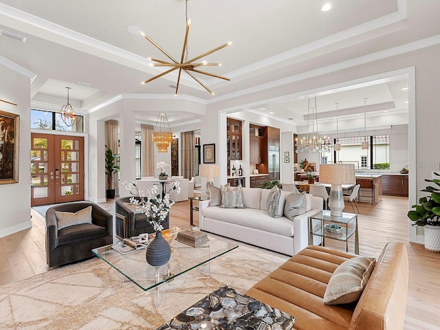 living room with crown molding, light hardwood / wood-style flooring, a tray ceiling, french doors, and a chandelier