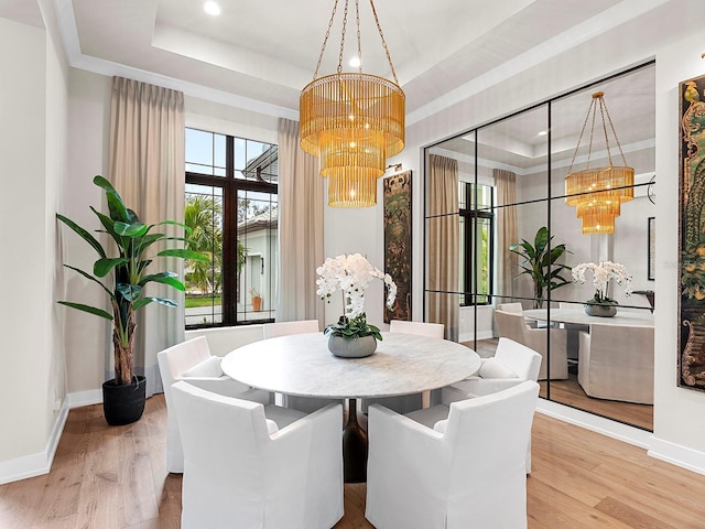 dining room featuring wood-type flooring, a raised ceiling, and a notable chandelier