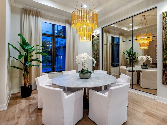 dining area with a chandelier, a raised ceiling, and hardwood / wood-style floors