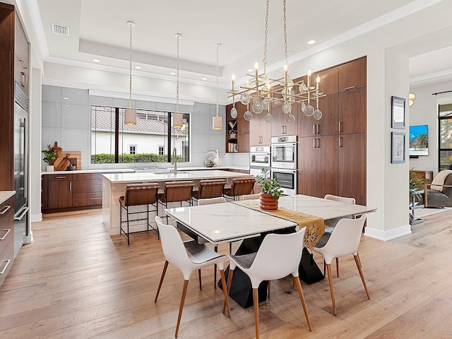 dining space featuring plenty of natural light, a tray ceiling, and light hardwood / wood-style floors