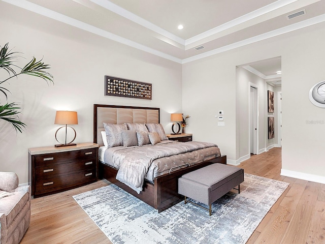 bedroom with crown molding, a raised ceiling, and light wood-type flooring