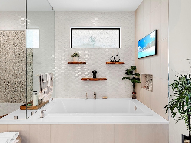 bathroom with plus walk in shower, plenty of natural light, and tile walls