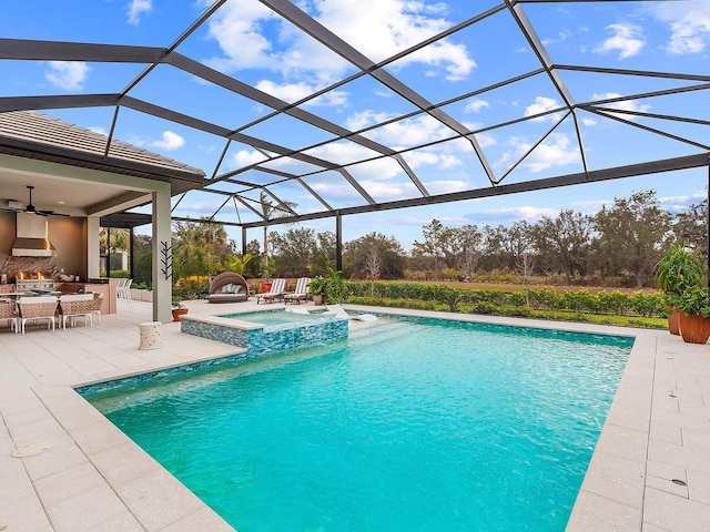 view of swimming pool with a lanai, ceiling fan, a patio area, an outdoor fireplace, and an in ground hot tub