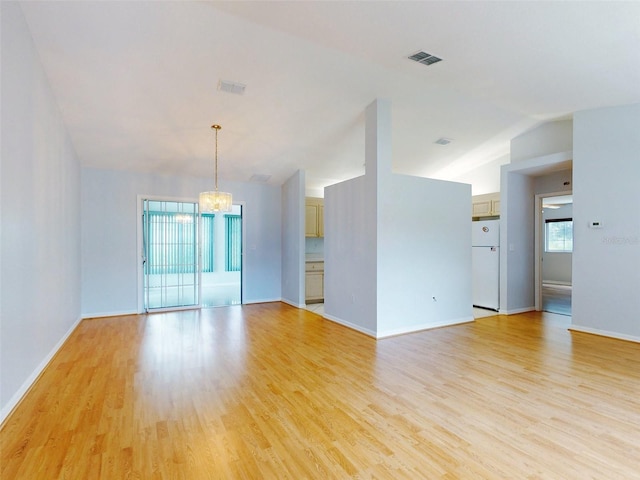 unfurnished room featuring light wood-type flooring, vaulted ceiling, and plenty of natural light