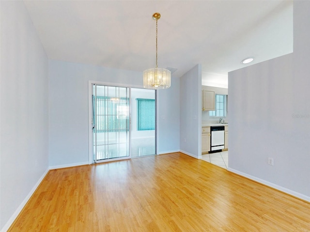 unfurnished room with sink, light wood-type flooring, and a chandelier