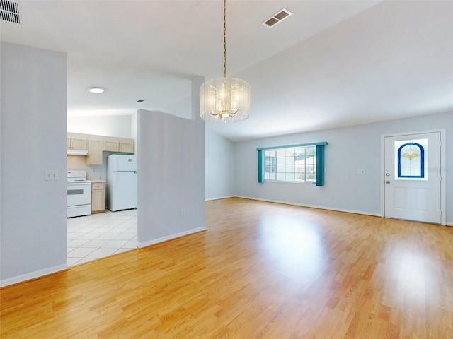 interior space featuring a chandelier, light wood-type flooring, and vaulted ceiling