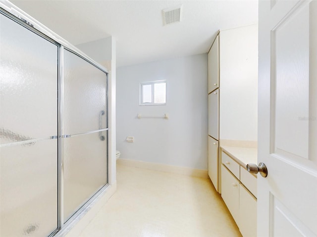 bathroom featuring toilet, vanity, and a shower with shower door