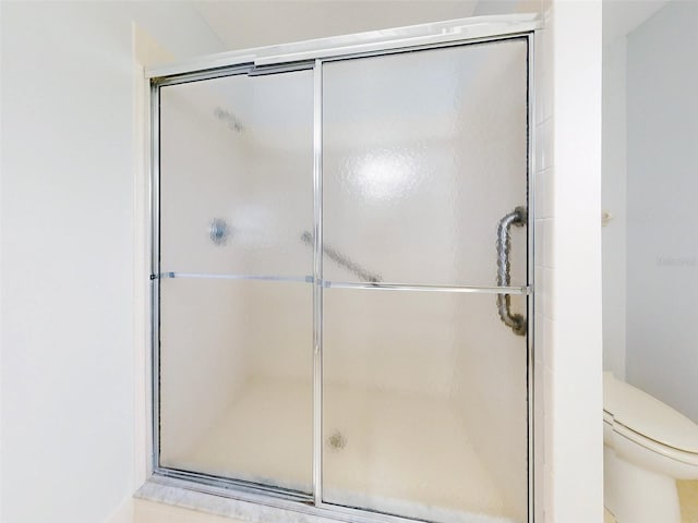 bathroom featuring toilet and a shower with door