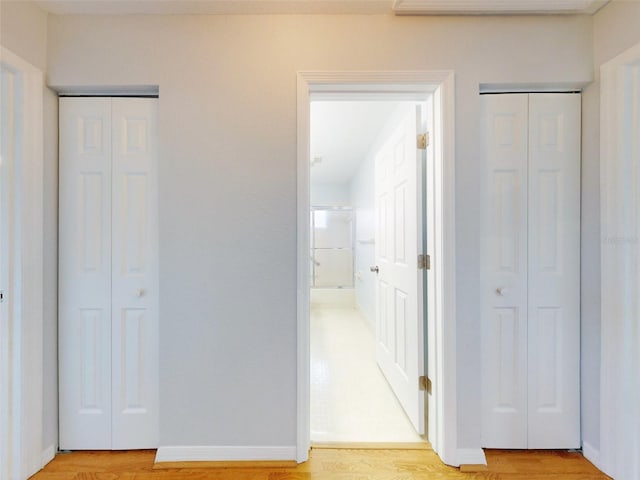 unfurnished bedroom featuring wood-type flooring and two closets