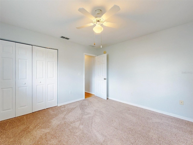 unfurnished bedroom featuring light colored carpet, ceiling fan, and a closet