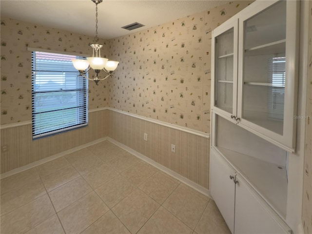 unfurnished dining area with a notable chandelier and light tile patterned flooring