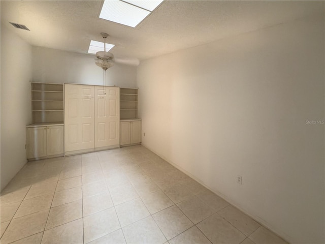 spare room with a skylight and light tile patterned flooring