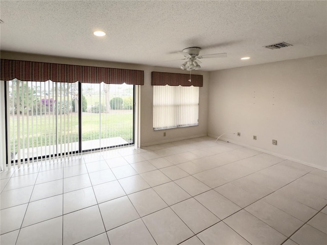 empty room with ceiling fan, light tile patterned floors, and a textured ceiling