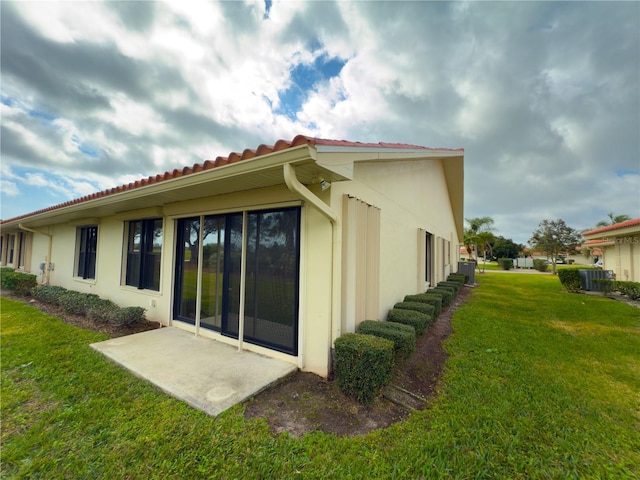 back of house with a patio area and a lawn