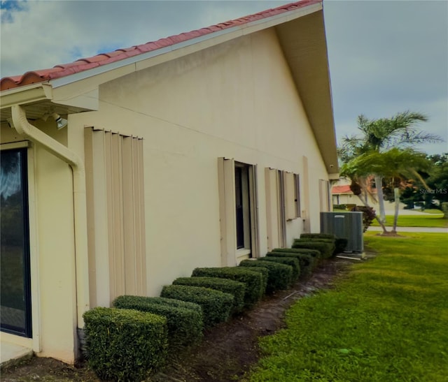 view of home's exterior with a lawn and central AC unit