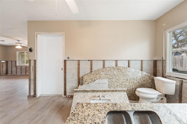 bathroom with toilet, hardwood / wood-style flooring, ceiling fan, and plenty of natural light