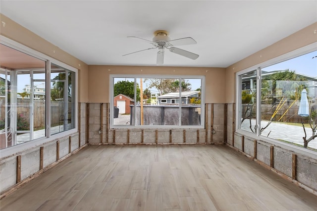 unfurnished sunroom with ceiling fan and a wealth of natural light