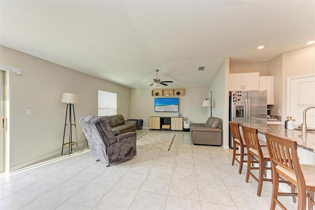 living room featuring ceiling fan, light tile patterned floors, and sink