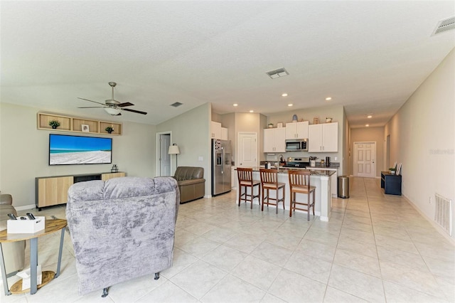 tiled living room featuring ceiling fan and a textured ceiling