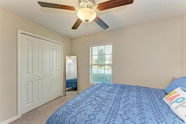 bedroom featuring ceiling fan, light colored carpet, a closet, and a textured ceiling