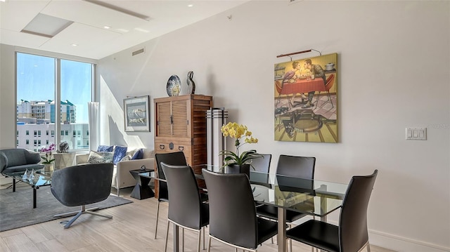 dining area with light hardwood / wood-style floors and a wall of windows