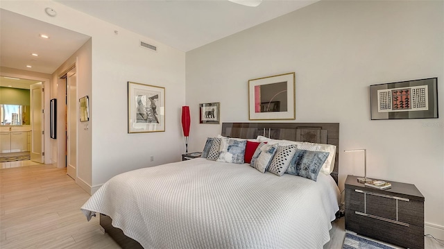 bedroom featuring ensuite bath and light wood-type flooring