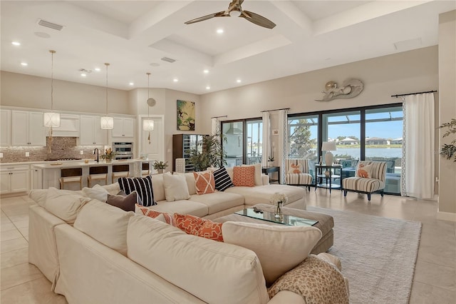 living room with coffered ceiling, a high ceiling, and a water view