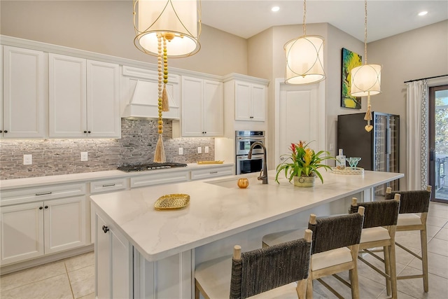 kitchen with hanging light fixtures, an island with sink, white cabinets, and appliances with stainless steel finishes