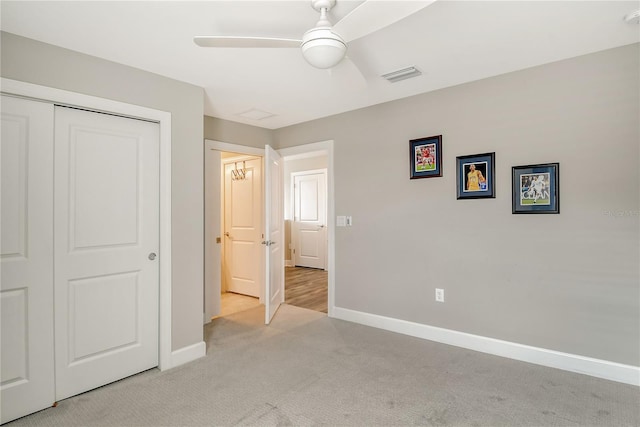 unfurnished bedroom featuring light colored carpet, ceiling fan, and a closet