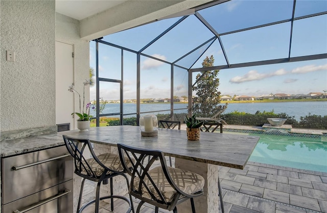 view of patio / terrace featuring a water view and glass enclosure