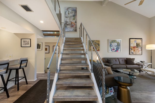 stairway featuring ceiling fan, lofted ceiling with beams, and wood-type flooring