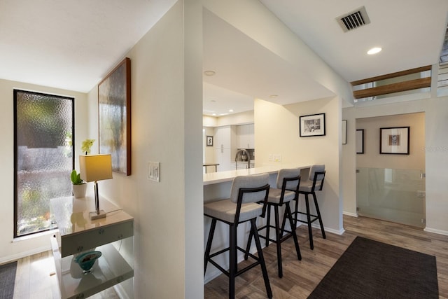 kitchen with a breakfast bar, white cabinets, kitchen peninsula, and light wood-type flooring