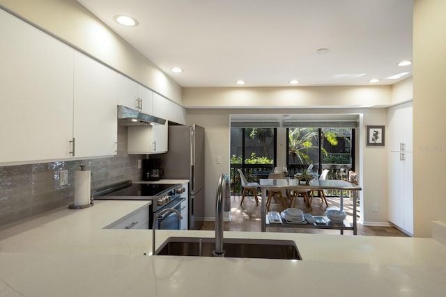 kitchen featuring backsplash, hardwood / wood-style floors, sink, appliances with stainless steel finishes, and white cabinets