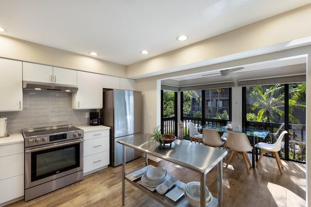 kitchen with white cabinetry, stainless steel appliances, decorative backsplash, light wood-type flooring, and a wealth of natural light