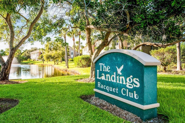 community sign with a water view and a yard