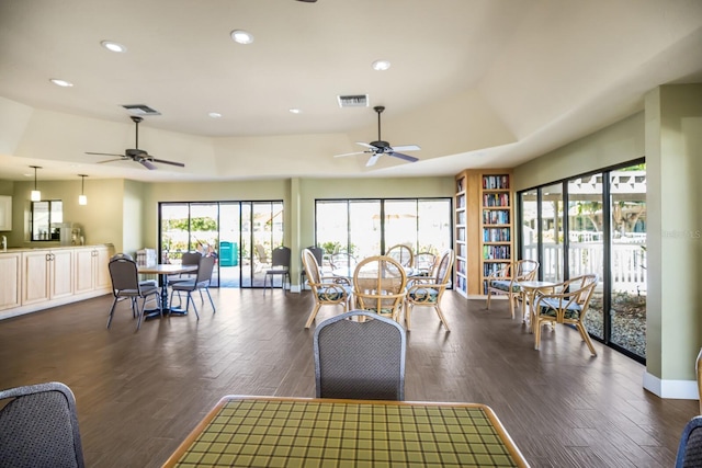 interior space with ceiling fan, dark hardwood / wood-style floors, and a tray ceiling