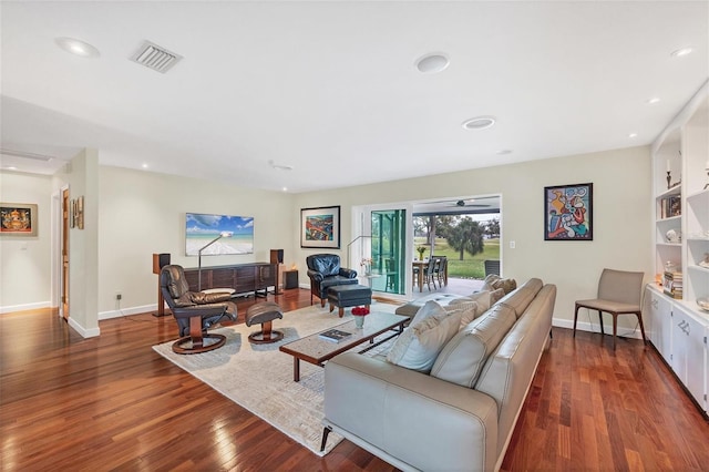 living room featuring built in shelves and dark hardwood / wood-style flooring