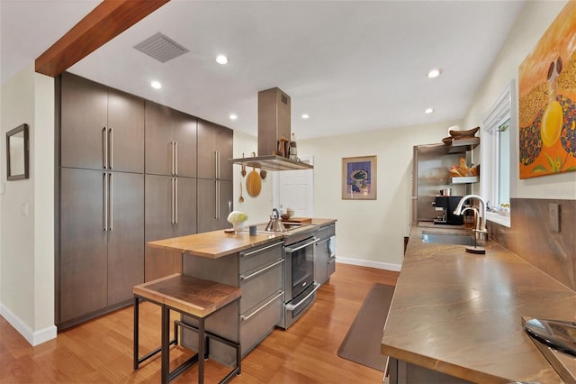 kitchen with sink, island range hood, stainless steel electric stove, and light hardwood / wood-style floors