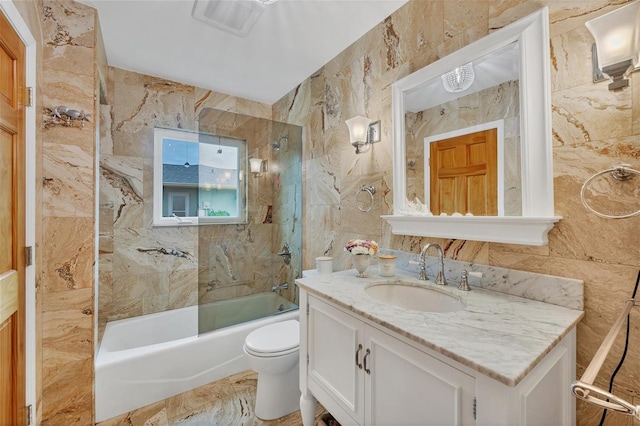 full bathroom featuring toilet, tile walls, vanity, and tiled shower / bath combo