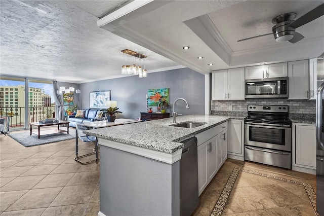 kitchen with kitchen peninsula, a raised ceiling, sink, appliances with stainless steel finishes, and backsplash